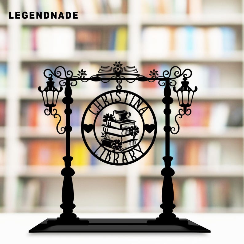 May include: Black metal sign with the text "CHRISTINA LIBRARY" in a circular design, featuring stacked books, a teacup, and floral accents. The sign is supported by two lamp posts and a base, with the word "LEGENDNADE" at the top.