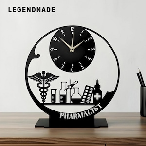 May include: A black pharmacist-themed desk clock with a circular design. The clock face is black with white numerals. The design includes a caduceus, laboratory equipment, and the word "PHARMACIST". The brand name "LEGENDNADE" is at the top.