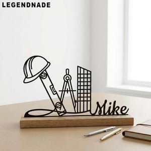 May include: Black metal architectural desk ornament with a hard hat, level, compass, and building silhouette on a wooden base. The name "Mike" is scripted on the base. The brand name "LEGENDNADE" is at the top.