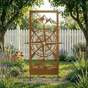 May include: A decorative metal garden screen with a compass rose design, mountains, and waves. The screen is made of rusty brown metal and is set in a garden with a white picket fence in the background.