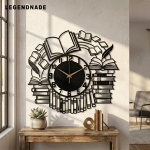 May include: A black wall clock featuring a circular face with gold hands and numbers, surrounded by a decorative metal cutout design of stacked books, open books, and feathers. The text LEGENDNADE is visible in the upper left corner.