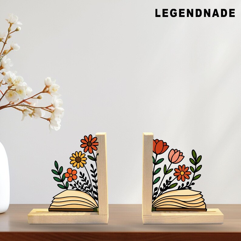 May include: Two wooden bookends with floral designs. Each bookend features a light-colored wooden base and upright support. The floral designs include orange, yellow, and pink flowers with green leaves. The text "LEGENDNADE" is at the top.