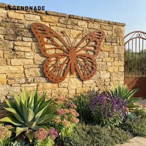 Può includere: Una grande scultura da parete in metallo color ruggine a forma di farfalla con intricati motivi alari ritagliati. La farfalla è montata su un muro di pietra marrone chiaro. Il testo LEGENDNADE è visibile nell'angolo in alto a sinistra.