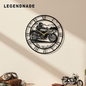 Könnte beinhalten: Schwarze Metall-Wanduhr mit einem Motorradfahrer auf einer kurvenreichen Straße, römischen Ziffern und dem Namen "Mr. Wallace". Die Uhrzeiger sind goldfarben. Der Markenname "LEGENDNADE" befindet sich oben links.