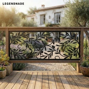 May include: A black metal railing panel featuring a decorative laser-cut pattern of olive branches with leaves and small fruits. The rectangular panel is framed by a wooden structure, positioned on a wooden deck overlooking a garden and house.