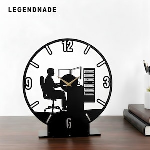 May include: Black desk clock featuring a silhouette of a person at a computer, with the text "LEGENDNADE" at the top. The clock face has gold hands and the numbers 3, 6, 9, and 12.