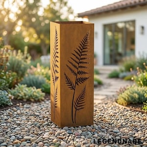 Può includere: Una colonna da giardino alta e rettangolare in metallo color ruggine, caratterizzata da sagome di foglie di felce tagliate al laser sulla parte anteriore. La struttura presenta una finitura ossidata e un'apertura cava sulla sommità.