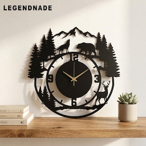 May include: Black metal wall clock with a nature-themed design. The clock features a circular face with gold hands, surrounded by silhouettes of trees, mountains, a wolf, a bear, and a deer. The word "LEGENDNADE" is at the top.