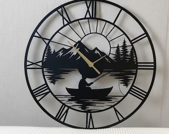 May include: Black metal wall clock with a nature scene featuring a person fishing in a boat, mountains, and trees. The clock has Roman numerals and gold-colored hands. The brand name "LEGENDNADE" is at the top.