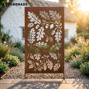May include: A rectangular metal garden screen with a rust-colored finish featuring a laser-cut pattern of oak leaves and acorns. The word LEGENDNADE is printed in the upper left corner. The screen stands upright on a stone patio surface.