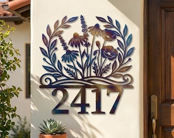 May include: A metal wall sign featuring the house number 2417 in a bold font, topped with a decorative cutout of wildflowers and leafy branches. The metal has a heat-treated finish with iridescent blue, purple, and bronze color gradients.