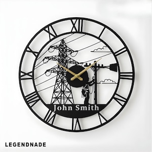 May include: Black metal wall clock with Roman numerals and a cut-out design featuring a power pylon, utility worker, and the name "John Smith." The clock hands are gold-colored.
