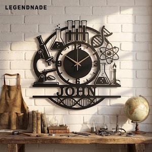 May include: A black circular wall clock featuring science-themed cutouts including a microscope, test tubes, a DNA strand, an atom, and beakers. The centre dial has gold hands and the name JOHN is displayed in bold capital letters at the bottom.