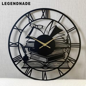 May include: Black metal wall clock with Roman numerals, featuring a design of books, glasses, a quill, and a candle. The clock hands are gold. The word "LEGENDNADE" is at the top.