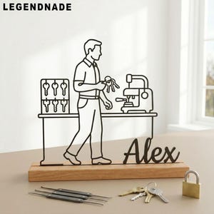 May include: A black metal key maker figurine with the name "Alex" on a wooden base. The figurine depicts a key maker with keys, a key cutting machine, and a key rack. A padlock and keys are also present.