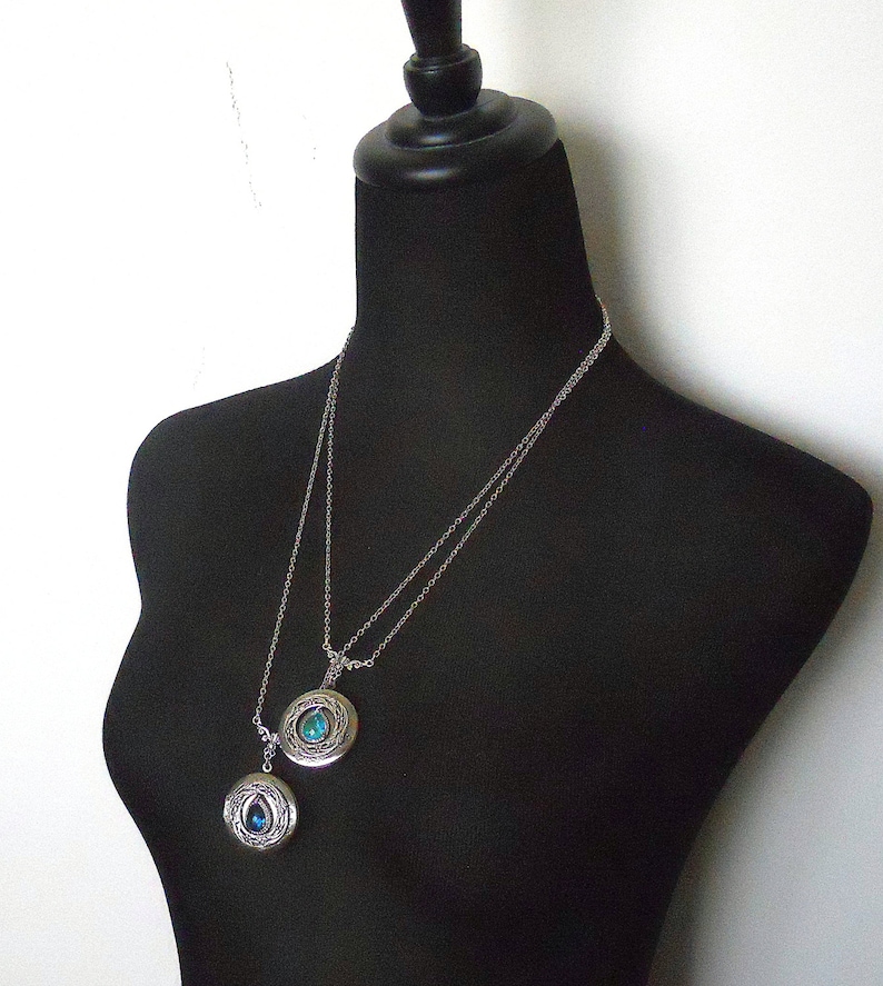 Puede incluir: Dos collares de plata con colgantes adornados con piedras preciosas azules. Los colgantes son redondos y tienen un dise&ntilde;o detallado.