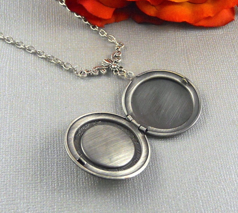 Puede incluir: Collar con dije de plata con dise&ntilde;o floral. El dije est&aacute; abierto, revelando un interior en blanco.