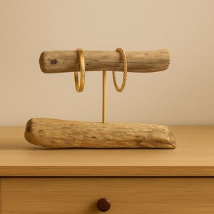 Close-up of multiple bracelets hanging on the driftwood rod, showing how jewelry wraps around the natural wood grain.