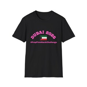 Könnte beinhalten: Schwarzes T-Shirt mit dem pinkfarbenen Schriftzug "DUBAI 2026", der sich über einer kleinen Kuwait-Flagge wölbt. Darunter steht der Text "#PropFirmHackChallenge" in Pink. Das T-Shirt hat einen Rundhalsausschnitt und kurze Ärmel.