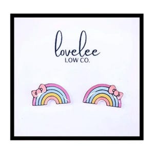 May include: A pair of rainbow-themed stud earrings with a pink bow on each. The earrings are on a white background with the text "lovelee LOW CO."