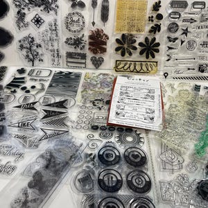 May include: A collection of clear rubber stamps with various designs, including words, patterns, and images. The stamps are arranged on a white surface. Some of the stamps feature the words "Celebrate", "Joy", "Special Day", and "This", "Like", "Cute".