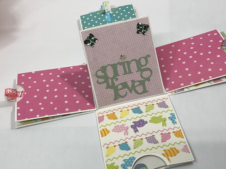 May include: A pink and white polka dot paper box with a light pink panel that says "spring fever" in green letters. The box is decorated with butterflies and has a light blue and white polka dot panel on the top.