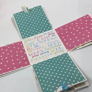 May include: A pink and blue patterned paper box with a white background. The box is decorated with the words "Easter", "Spring", "Flowers", "Rain", "Happy", "Show", "Play", "Wers", "Shower", and "Easter".
