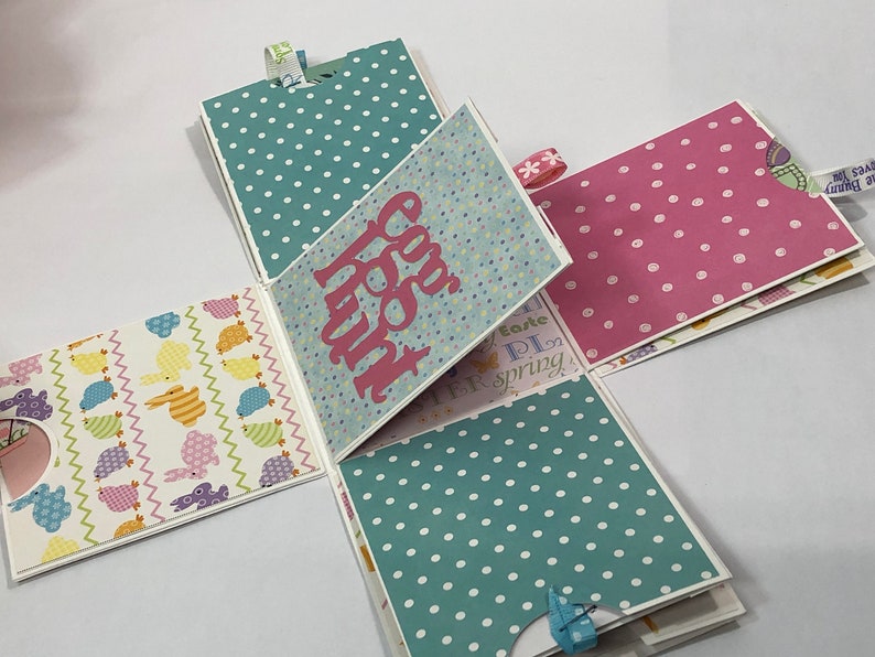 May include: A multi-page paper craft with a spring theme. The pages are decorated with various patterns, including polka dots, birds, and bunnies. The front page features the text "Happy Easter".