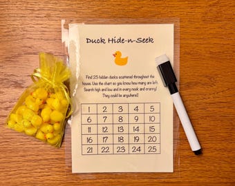 May include: A Duck Hide-n-Seek game set. Includes a bag of yellow rubber ducks, a laminated game sheet with a chart, and a dry-erase marker. The game sheet has the text "Duck Hide-n-Seek" and instructions.