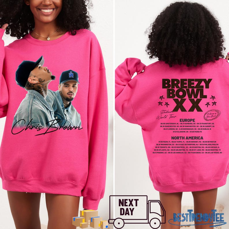 May include: A bright pink sweatshirt featuring a graphic of Chris Brown on the front. The back of the sweatshirt displays the text "Breezy Bowl XX" with a list of tour dates for Europe and North America.
