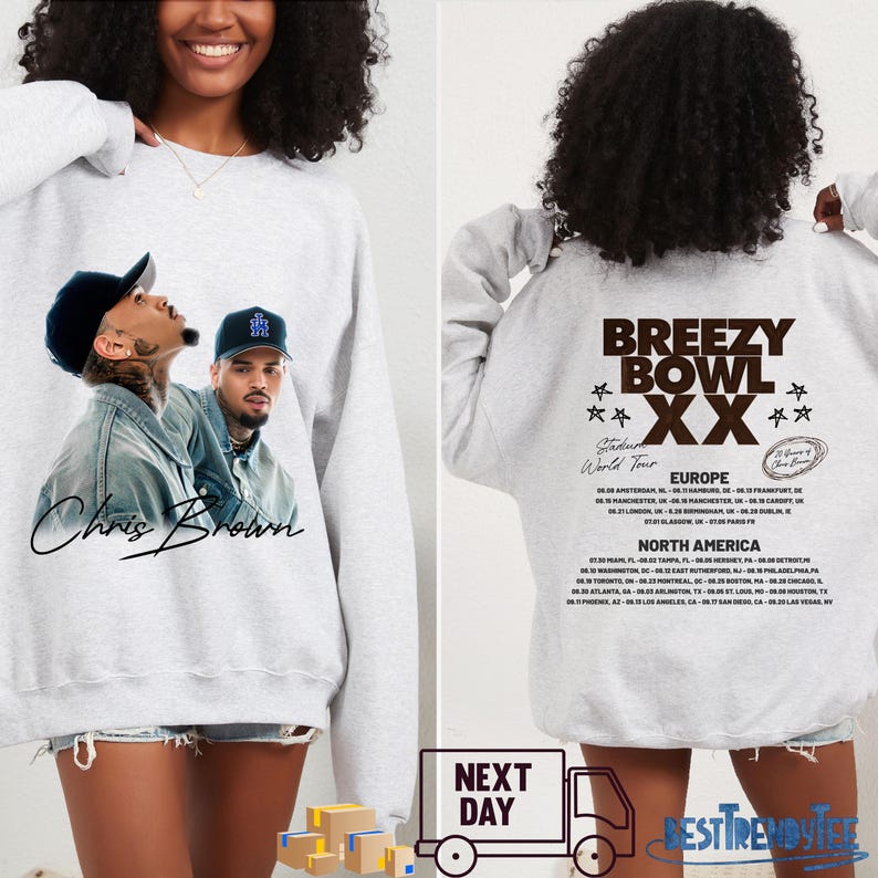 May include: A light gray sweatshirt featuring a graphic of Chris Brown on the front. The back of the sweatshirt displays "Breezy Bowl XX" tour dates for Europe and North America. The sweatshirt is a casual style.