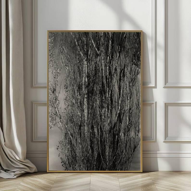 May include: Black and white framed art print featuring a close-up of a tree trunk and branches. The artwork is displayed in a gold frame and leans against a white wall with decorative molding. The image has a natural, organic theme.