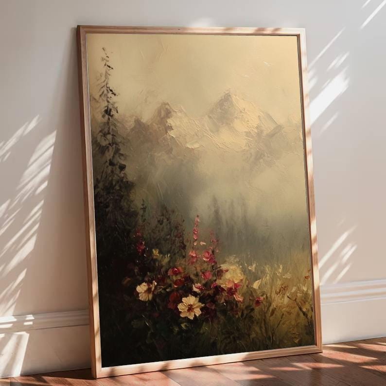 May include: An oil painting in a light wood frame depicts a mountain landscape. The artwork features a misty forest, wildflowers in shades of red and yellow, and snow-capped mountains in the background. The color palette is muted with a vintage aesthetic.