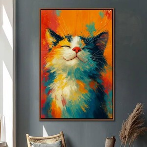 May include: A framed painting of a smiling cat with closed eyes. The cat's fur is a mix of blue, orange, white, and yellow brushstrokes against a vibrant orange background. The cat has a red nose and black ears.
