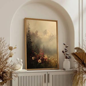 May include: A framed landscape painting with a gold-colored frame. The artwork depicts a mountain scene with a forest and colorful flowers in the foreground. The painting is displayed on a white cabinet.