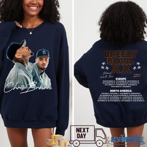 May include: Navy blue sweatshirt featuring a graphic of Chris Brown with his signature. The front design includes two images of the artist. The back of the sweatshirt displays "Breezy Bowl XX" and tour dates for Europe and North America.