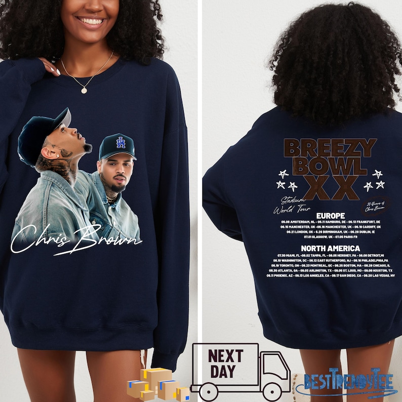 May include: Navy blue sweatshirt featuring a graphic of Chris Brown with his signature. The front design includes two images of the artist. The back of the sweatshirt displays "Breezy Bowl XX" and tour dates for Europe and North America.