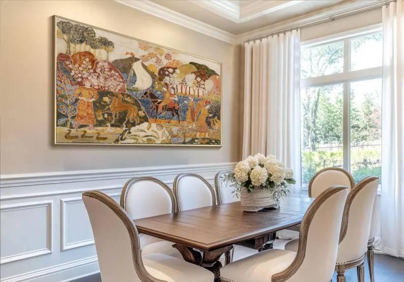 May include: An ornate framed painting depicting a historical scene hangs above a wooden dining table. The table is surrounded by white upholstered chairs. A vase of white flowers sits in the center of the table, and white curtains frame a window.