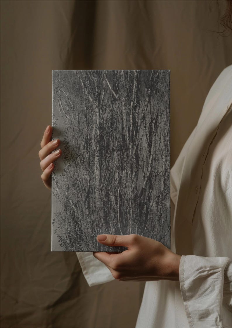 May include: A rectangular canvas print featuring a grayscale image of a dense thicket of trees and branches. The artwork is held by a person wearing a white shirt. The image has a textured appearance.