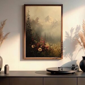 May include: A framed landscape painting depicts a mountain scene with flowers. Two dark vases with dried plants flank the painting. A record player sits on a dark cabinet, creating a serene, artistic display.