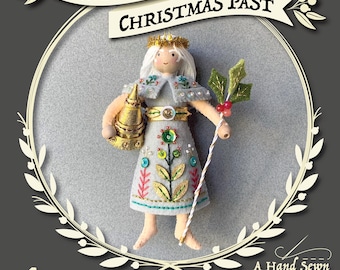 May include: A hand-sewn felt ornament pattern for a Christmas angel with a gold crown, a gold and white robe, and a holly sprig. The pattern is part of the Ebenezer Ornament Series by Larissa Holland.