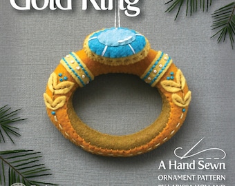 May include: A felt Christmas ornament shaped like a gold ring with a blue gemstone. The ornament is part of a 12 Days of Christmas series.