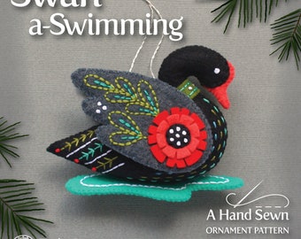 May include: A felt ornament pattern for a black swan with a red flower on its wing, swimming on a turquoise water base. The pattern is part of a Twelve Days Ornament Series.