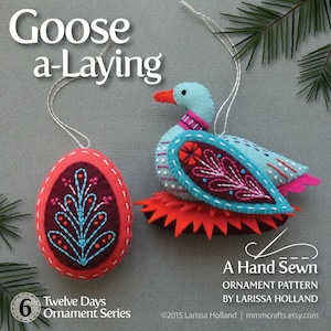 Könnte beinhalten: Ein Filz-Ornament-Muster für eine Gans, die ein Ei legt. Die Gans ist blau mit rosa und roten Akzenten. Das Ei ist rot mit einem burgunderroten und blauen Design. Das Muster trägt den Titel "Goose a-Laying" und ist Teil einer "Twelve Days Ornament Series".