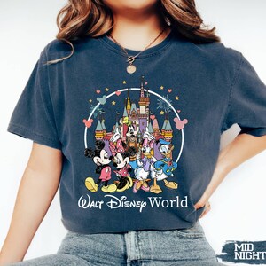 Puede incluir: Una camiseta azul marino con un gr&aacute;fico de Mickey Mouse, Minnie Mouse, Donald Duck, Goofy y Pluto frente al Castillo de Cenicienta. El texto "Walt Disney World" est&aacute; impreso debajo del gr&aacute;fico.