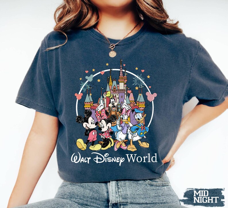 Puede incluir: Una camiseta azul marino con un gr&aacute;fico de Mickey Mouse, Minnie Mouse, Donald Duck, Goofy y Pluto frente al Castillo de Cenicienta. El texto "Walt Disney World" est&aacute; impreso debajo del gr&aacute;fico.