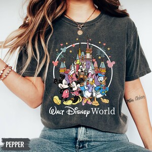 Puede incluir: Una camiseta gris oscuro con un gr&aacute;fico de estilo vintage de Mickey Mouse y sus amigos frente al Castillo de Cenicienta en Walt Disney World. El texto "Walt Disney World" est&aacute; impreso en blanco debajo del gr&aacute;fico.