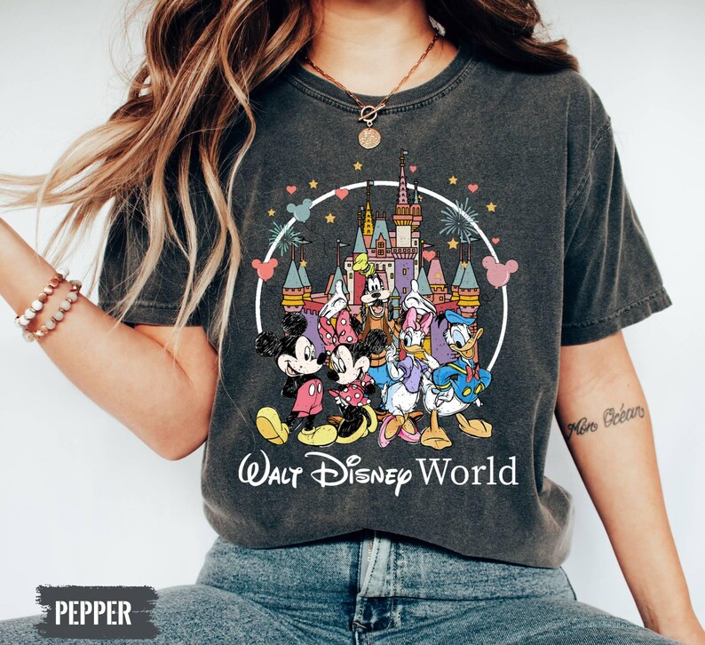 Puede incluir: Una camiseta gris oscuro con un gr&aacute;fico de estilo vintage de Mickey Mouse y sus amigos frente al Castillo de Cenicienta en Walt Disney World. El texto "Walt Disney World" est&aacute; impreso en blanco debajo del gr&aacute;fico.