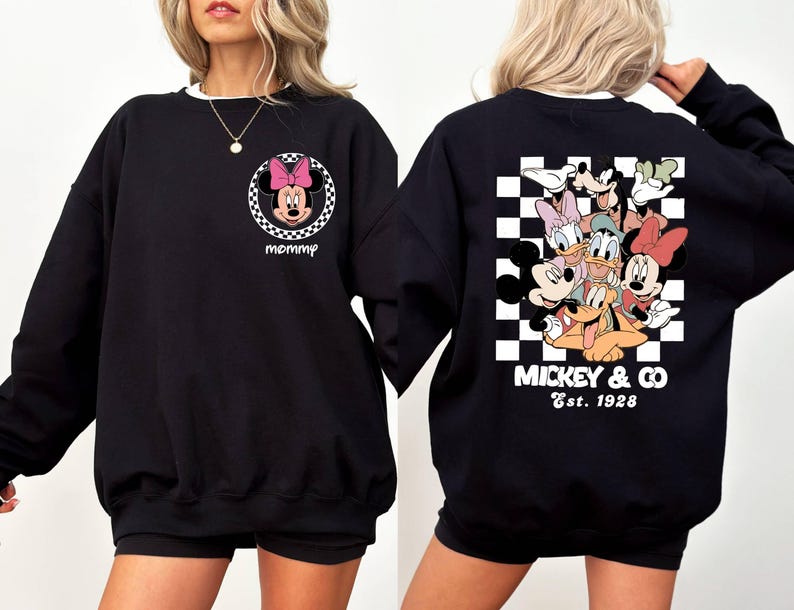 May include: Black sweatshirt with a checkered pattern on the back and a Mickey Mouse and friends graphic. The text "Mickey & Co. Est. 1928" is printed below the graphic. The front of the sweatshirt has a small graphic of Minnie Mouse with the word "mommy" printed below it.