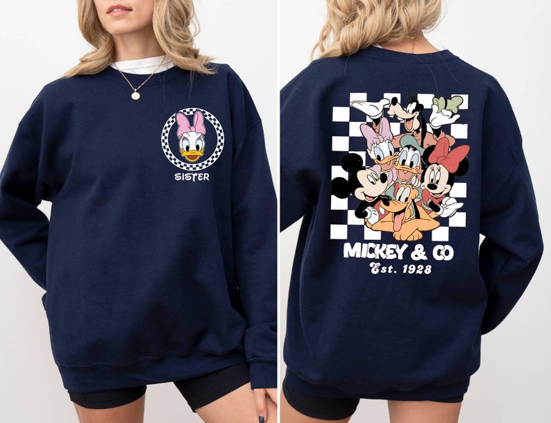 Puede incluir: Sudadera azul marino con un patr&oacute;n a cuadros y un gr&aacute;fico de Mickey Mouse y sus amigos en la espalda. La parte delantera de la sudadera tiene un gr&aacute;fico de Daisy Duck con la palabra "Sister" debajo.